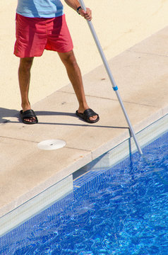 Guy cleaning the swimming pool with a brush