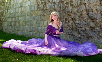 blonde girl in violet dress sitting on the grass