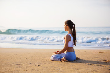 Fototapeta na wymiar Caucasian woman practicing yoga at seashore of tropic ocean