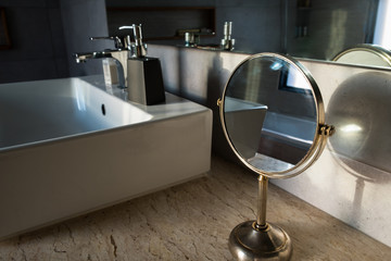 Focus on the round table mirror beside luxury white sink in the toilet