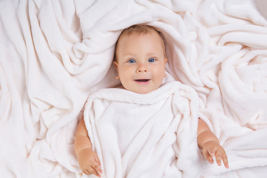 Cute smiling baby under towel after bath