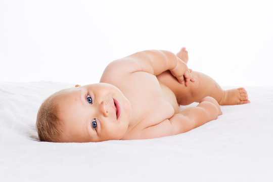 Cute smiling baby lying on towel isolated on white