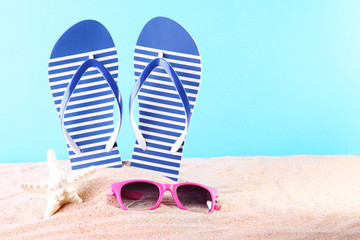 Blue flip flops with sunglasses and starfish on the beach sand