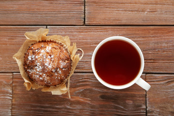 Tasty muffin with cup of tea on brown wooden table