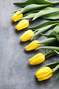 Bouquet of yellow tulips on grey wooden table