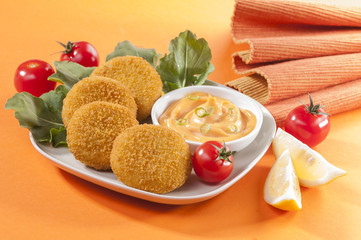 Chicken and cheese fried tikki with lemon and cherry tomato on orange background