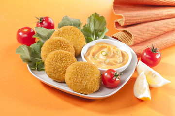 Chicken and cheese fried tikki with lemon and cherry tomato on orange background