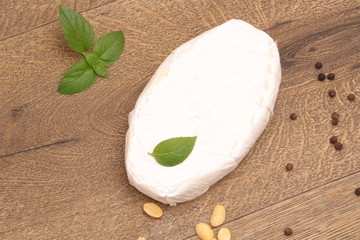 Brie cheese on a wooden background with basil