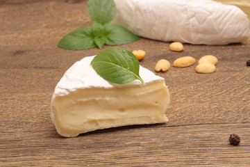 Brie cheese on a wooden background with basil