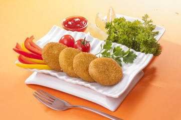 Chicken and cheese fried tikki with lemon and cherry tomato on orange background