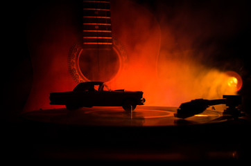 Vintage vinyl record playing on player and acoustic guitar on background with fire orange smoke. Blues concept.