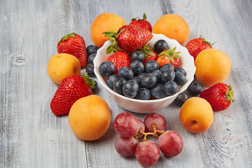 Strawberries, blueberries, apricot t on a wooden board