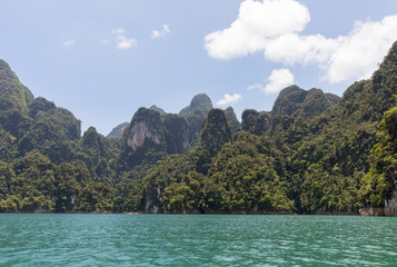 Obraz premium Shore of Ratchaprapha lake with tropical trees on a sunny day