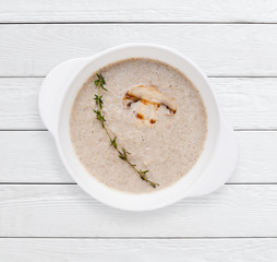 Delicious homemade cream of mushroom soup with slice of grilled champignon. Healthy food, delicacy, lunch dish concept. White wooden planks background.