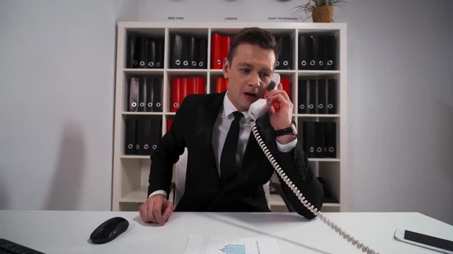 4k POV. Young Handsome businessman in formal suit ask You wait and precise some Your questions by telephone with his boss. Consultation customer service concept
