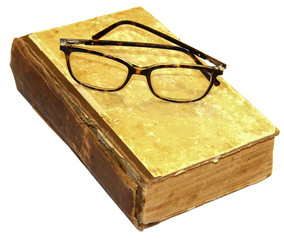 On an old book with a torn binding and a broken spine are glasses