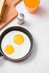 Top view of traditional healthy easy quick breakfast meal made of fried eggs served on a frying pan.