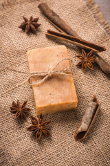 Handmade soap with cinnamon and anise star on wooden background.
