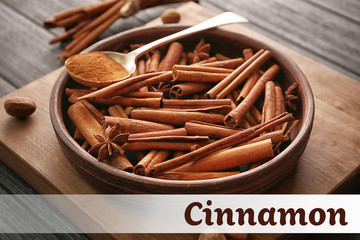 Bowl with cinnamon sticks and spoon of powder on wooden background