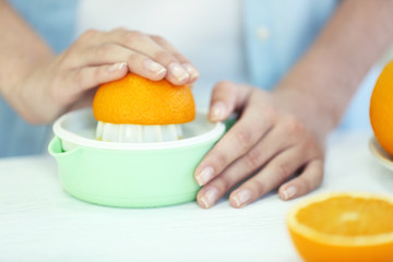 Female hands making orange juice on kitchen