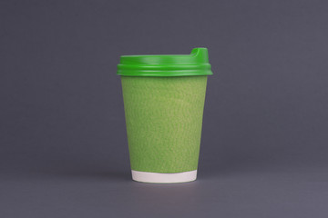 Green paper coffee cup. On grey background. Takeaway cup of coffee mock up