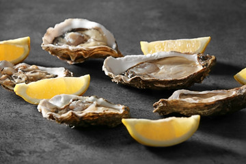Tasty fresh oysters with sliced juicy lemon on dark background. Aphrodisiac food for increasing...