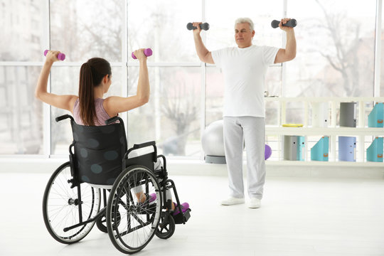 Young disabled woman with senior orthopedist in rehabilitation clinic