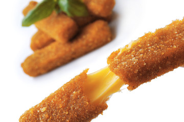 Broken deep fried stick with stretchy cheese on blurred background