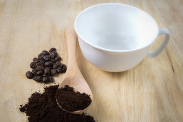 Roasted coffee and white coffee mug on wooden floor.
