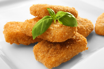 Cheese sticks with basil on plate, closeup