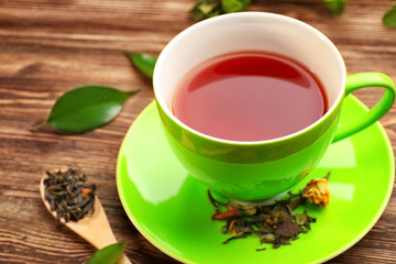 Cup of tea and spoon of brew on wooden background