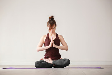 Young woman practicing yoga on light background indoors
