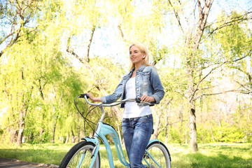 Obraz premium Happy young woman with bicycle in spring park