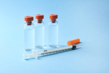Vaccine in vials with syringe on color background