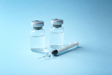 Vaccine in vials with syringe on color background