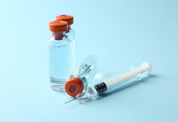 Vaccine in vials with syringe on color background