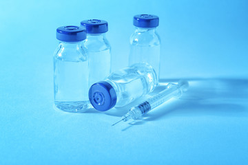 Vaccine in vials with syringe on color background