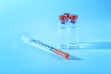 Vaccine in vials with syringe on color background