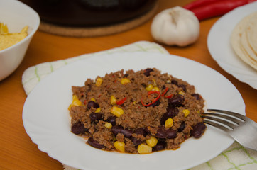 Chili con carne served on white plate with tortillas