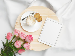 Colazione su vassoio a letto, cappuccino, biscotti, fiori e tablet