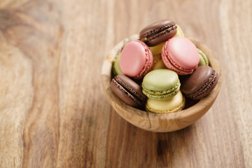assorted macarons in wood bowl on wooden table