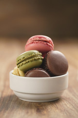 assorted macarons in white bowl on wooden table