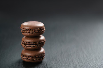 Fototapeta na wymiar chocolate macarons stacked on slate board