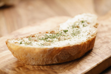 rustic wheat bread with butter and herbs on wood board