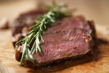 sliced medium rib eye steak with rosemary branch