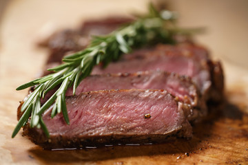sliced medium rib eye steak with rosemary branch