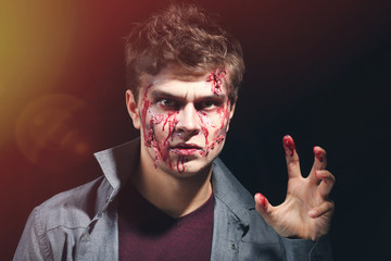 Young man with Halloween makeup on dark background