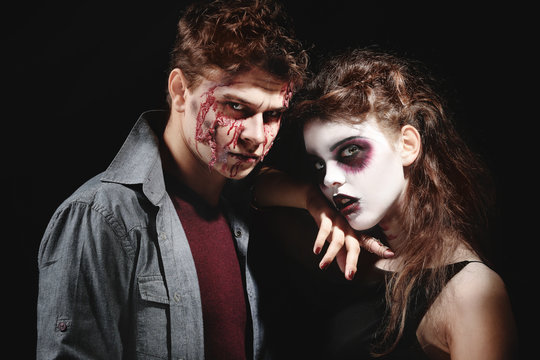 Young man and woman with Halloween makeup on dark background