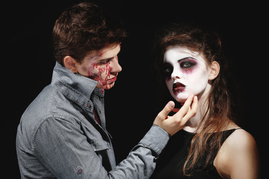 Young man and woman with Halloween makeup on dark background