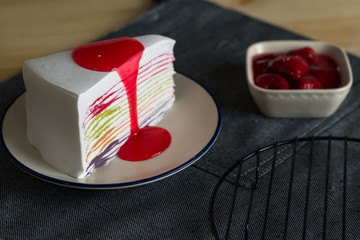 delicious sweet dessert bakery rainbow color layer crepe cake with fresh strawberry sauce